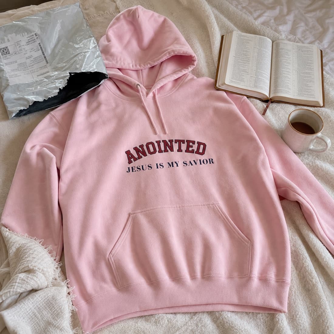 Light pink My Jesus hoodie laid on a bed after unboxing