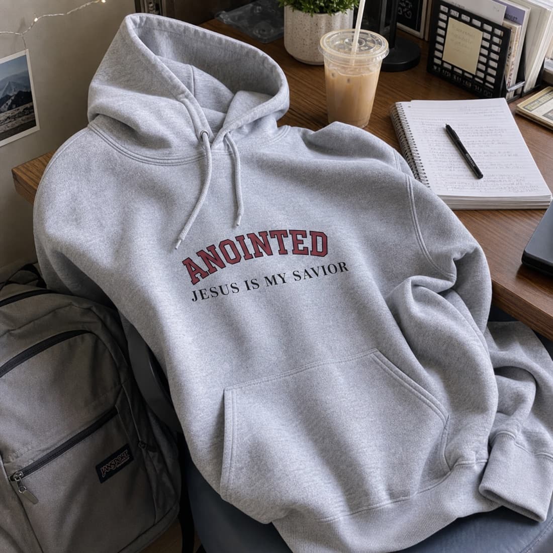 Sport grey My Jesus hoodie draped on a desk chair beside a backpack